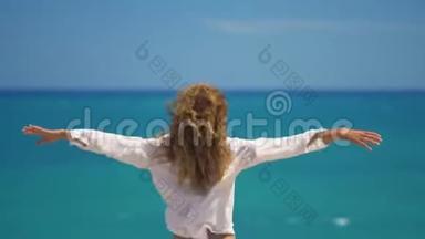 在美丽的海面上，年轻女子的头发随风飘动，双<strong>手举</strong>在悬崖之上。 概念自由